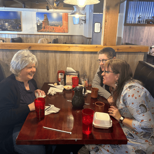 Sarah Wildey, right front, Tina Carpenter, right back, and Kathy Kendle, left, sitting around a table with Sarah making a face at Kathy. 